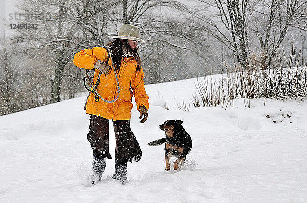 Frau geht mit ihrem Hund im Schnee spazieren