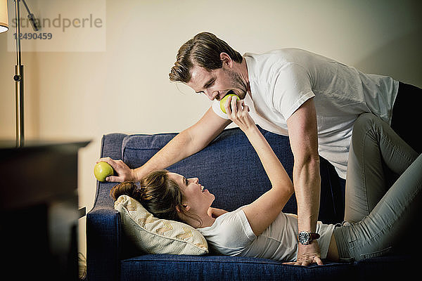 Ein Paar teilt einen Apfel zusammen auf dem Sofa in einem Hotelzimmer