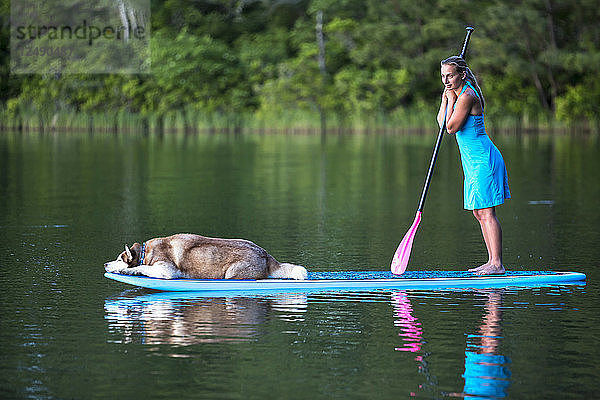 Frau mit ihrem Hund auf dem Stand Up Paddleboard
