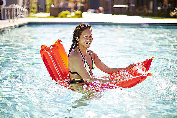 Glückliche asiatische Frau hat Spaß mit einem Luftbett im Pool