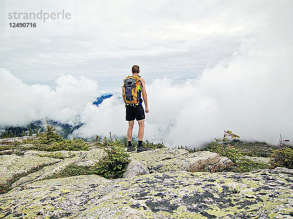 Ein Mann blickt vom Gipfel des Baldface Mountain  New Hampshire  auf die Wolken