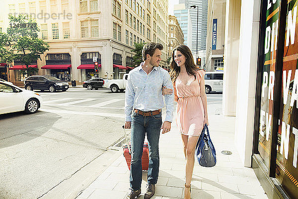 Junges Paar mit ihrem Gepäck zu Fuß Seite an Seite auf einem Fußweg in Dallas
