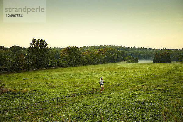 Eine Frau läuft durch ein Feld an einem nebligen Morgen
