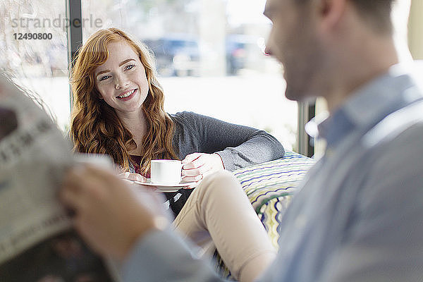 Ein hübsches junges Paar liest bei einem Kaffee in einer Cafeteria Zeitung.
