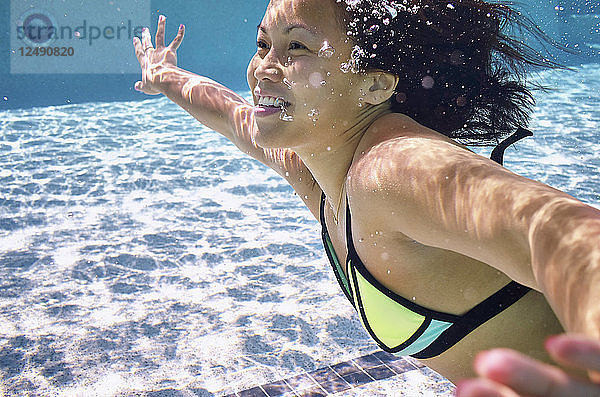 Junge Frau schwimmt unter Wasser im Pool
