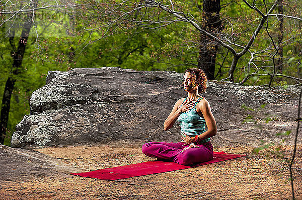 Frauen machen Atemübungen auf einer Yogamatte im Wald