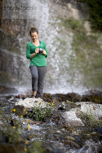 Frau mit Kamera stehend in der Nähe von Berg Wasserfall