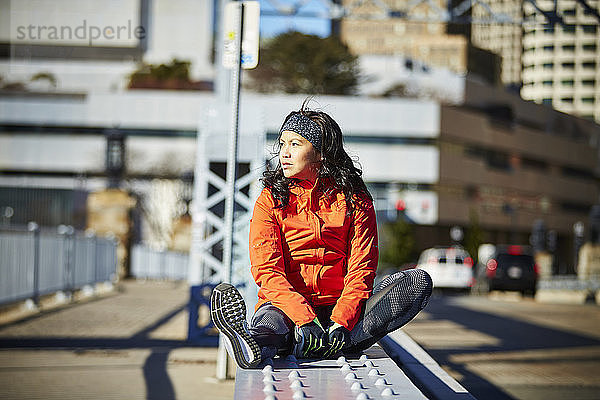 Ein junger asiatischer Läufer/Sportler in einer städtischen Umgebung in Ruhe.