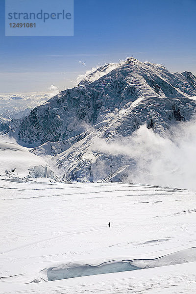 Entfernte Ansicht von Clark Fyans Wandern auf einer verschneiten Landschaft in Alaska.