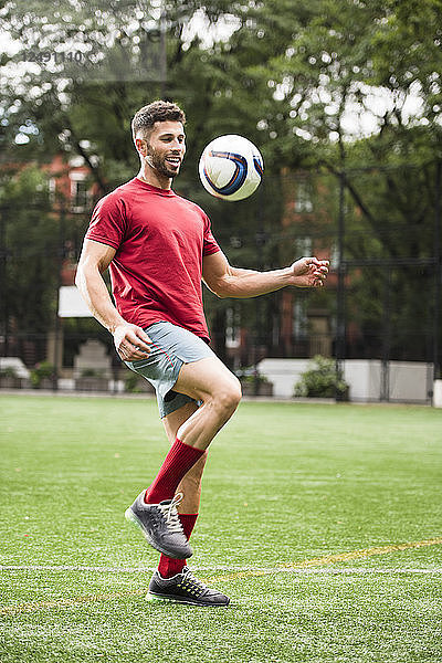 Ein Mann spielt Fußball auf einem Feld im Stadtpark