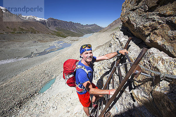 Ein männlicher Wanderer klettert über steile Leitern zum Pas des Chevres (Bergziegenpassage) auf halber Strecke der Haute Route  einer klassischen Wanderung zwischen Chamonix in Frankreich und Zermatt in der Schweiz. Für fitte Wanderer dauert sie zehn Tage.