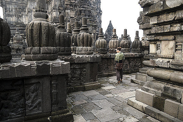 Eine junge Frau erkundet die Tempelanlagen von Prambanan in Indonesien. Der erste Tempel in Prambanan wurde 850 n. Chr. erbaut und gehört heute zum UNESCO-Weltkulturerbe.