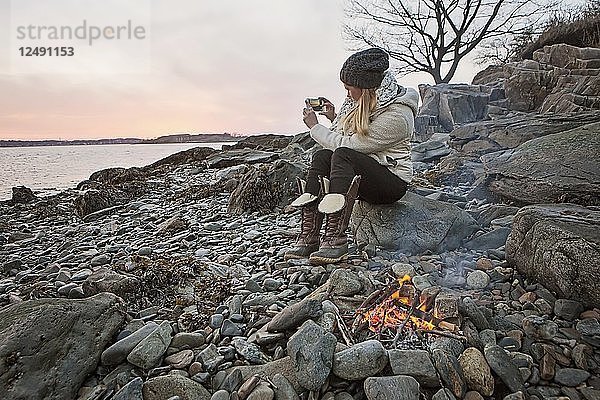 Frau  die mit ihrem Handy entlang der Küste von Maine ein Bild vom Fluss macht
