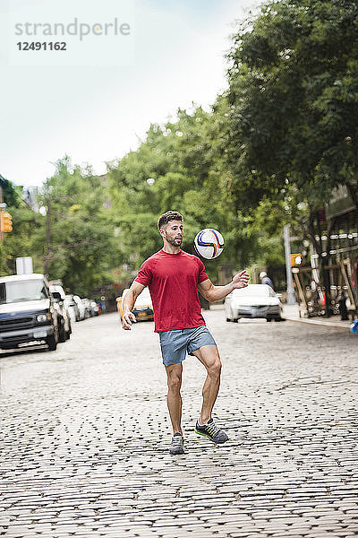 Sportler spielt Fußball auf den Straßen der Stadt