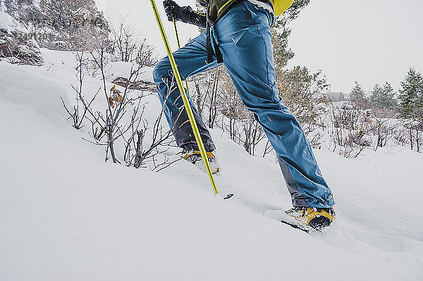 Nahaufnahme eines Männerbeins beim Wandern im Schnee