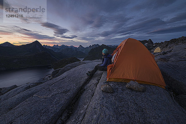 Wanderin sitzt im letzten Dämmerlicht des Spätsommers vor dem Zelt in der Nähe des Gipfels des Moldtind  Moskenes??y  Lofoten  Norwegen