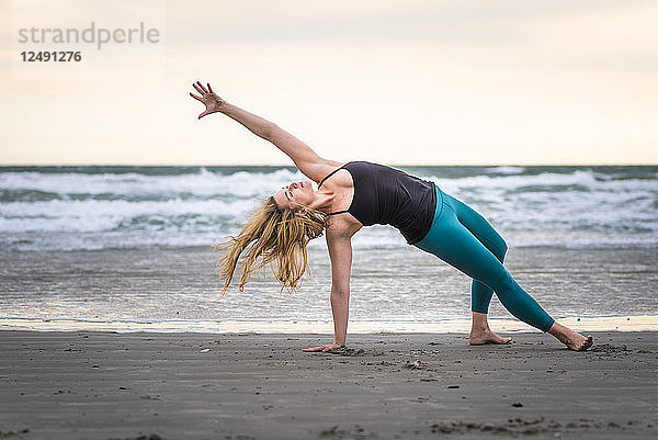 Frau macht Yoga an einem bewölkten Tag am Strand in Rhode Island