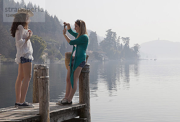 Zwei Teenager-Mädchen machen ein Foto am Ende eines See-Piers