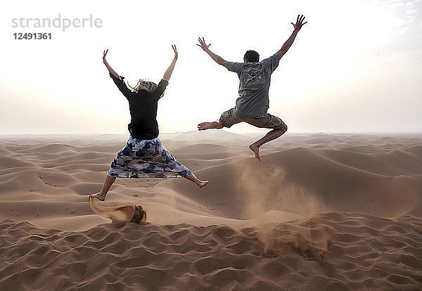 Menschen springen in den Chegaga-Dünen in der Wüste Sahara in Marokko.