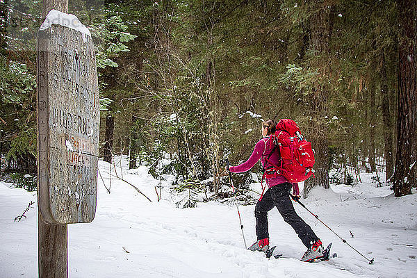 Eine Skitourengeherin fährt an einem Schild vorbei  das den Beginn der Selway-Bitterroot Wilderness in Montana markiert.