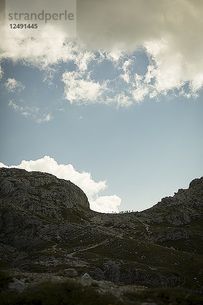 Die Silhouetten von Wanderern zeichnen sich vor einem blauen Himmel in der italienischen Dolomitenregion ab.