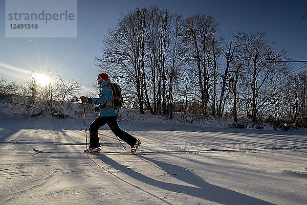 Ein Skifahrer fährt auf Tourenskiern einen zugefrorenen Fluss im südlichen Maine hinunter.