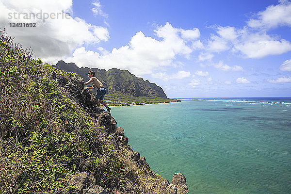 Männlicher Wanderer klettert auf Felsen am Ufer von Mokolii in Oahu  Hawaii