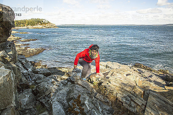Wanderer klettert um die Meeresklippen im Acadia National Park  Maine