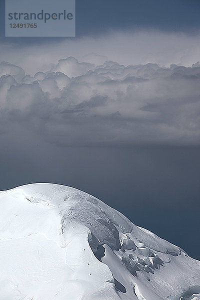 Bergsteiger sind kleine Pünktchen auf dem Weg zum Gipfel des Kahiltna Dome  einem Nachbargipfel des Mt McKinley. Dieser Berg wird von Alpinisten gerne bestiegen  um sich zu akklimatisieren. Die Wolken im Hintergrund verraten  dass ein Sturm aufzieht. Der Mount McKinley oder Denali ist der höchste Berg Nordamerikas mit einer Gipfelhöhe von 6.168 m über dem Meeresspiegel. Mit einer Höhe von rund 5.500 m (18.000 Fuß) ist er der höchste Berg  der vollständig über dem Meeresspiegel liegt. Gemessen an der topografischen Ausdehnung ist er nach dem Mount Everest und dem Aconcagua der drittgrößte Berg. Der McKinley befindet sich in der Alaska Range im Inneren des US-Bundesstaates Alaska und ist das Herzstück des Denali National Park and Preserve.