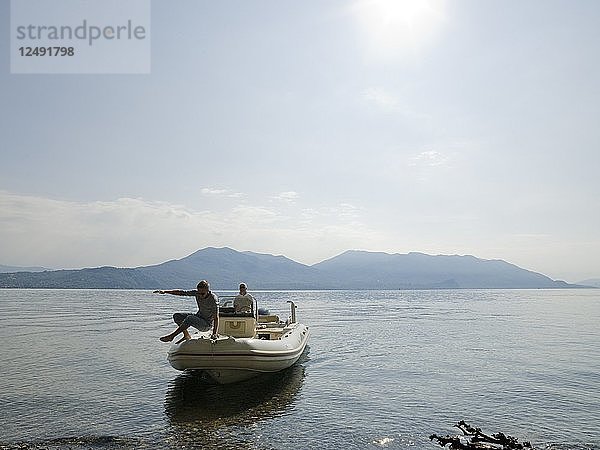 Vater und Sohn legen mit dem Schlauchboot am Seeufer an