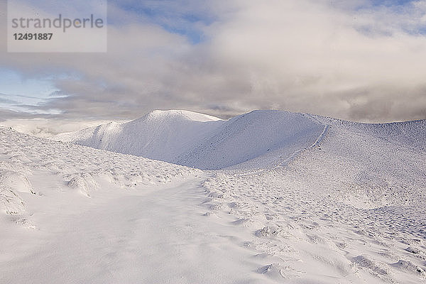 Ein schneebedeckter Pfad führt entlang eines Bergrückens zum Gipfel des Isthmus Peak  Neuseeland