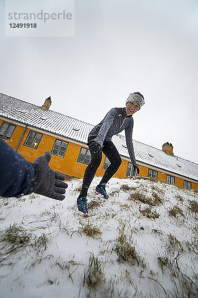 Lächelnde Läuferin wird vom Schneehang heruntergeholfen