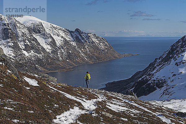 Wanderin beim Abstieg von einem felsigen Grat in Richtung Skjelfjorden auf den Lofoten  Norwegen
