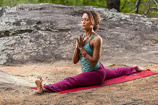 Frau macht Stretching auf Yoga-Matte im Wald