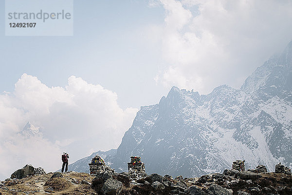 Ein Trekker hält inne  um die Berge des nepalesischen Himalayas auf dem Everest Base Camp Trek zu fotografieren.