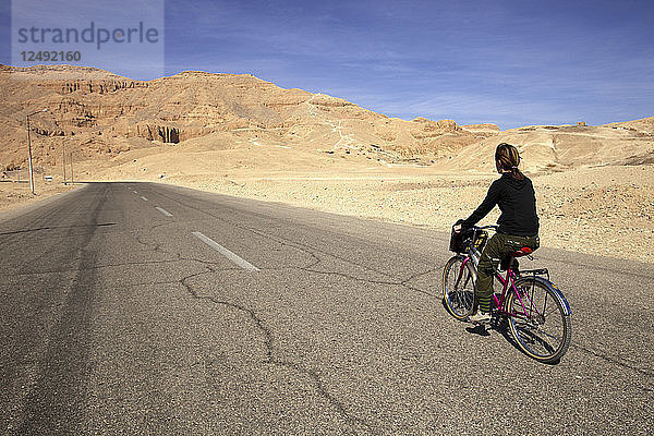 Person Riding Bicycle On Street of Desert Landscape