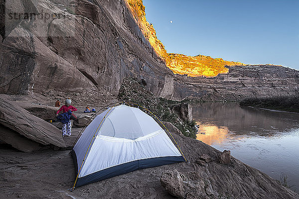 Ein junges Mädchen macht sich in einem Zelt auf dem Sandstein des Labyrinth Canyon Abschnitts des Green Rivers  Green River  Utah  bettfertig.