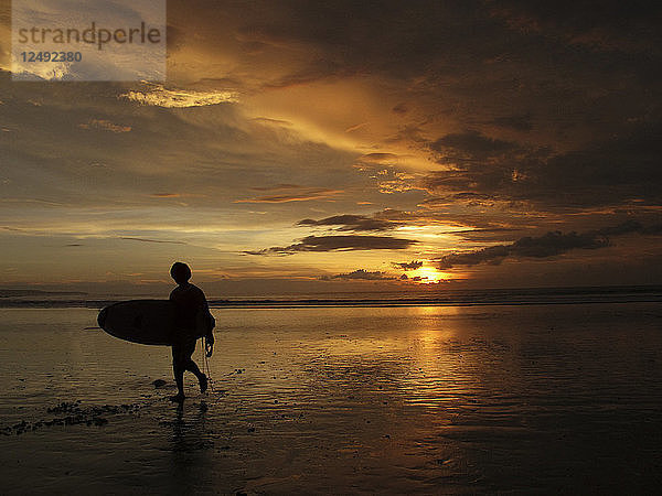 Ein Surfer  der am Ende des Tages zum Strand zurückkehrt. Ubud Kuta Strand Indonesien