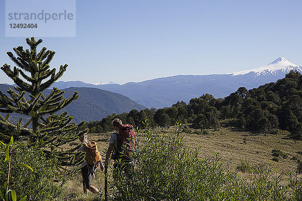 Wandererpaar auf Alpenkamm mit Vulkan im Hintergrund