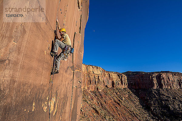 Ein Mann klettert einen schwierigen Riss namens Sig Sauer an der Pistol Whipped Wall in Indian Creek  Monticello  Utah  hoch.