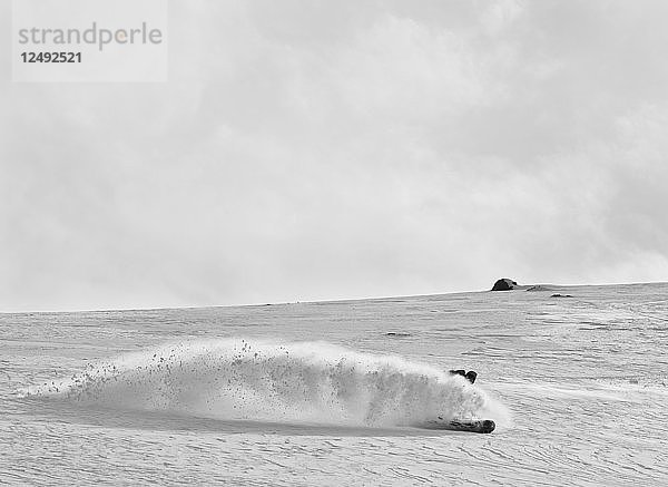 Ein Snowboarder macht eine Kurve und spritzt Puder in die Luft in Argentinien