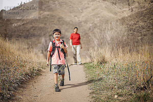 Ein 6-jähriger japanisch-amerikanischer Junge wandert mit seiner Mutter im Hintergrund auf dem Hewlett Gulch Trail  Colorado.