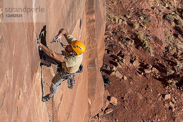 Ein Mann klettert einen schwierigen Riss namens Sig Sauer an der Pistol Whipped Wall in Indian Creek  Monticello  Utah  hoch.