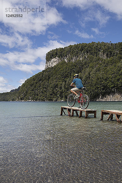 Fahrradfahrer betrachtet die Szene von einem kleinen Steg am Bergsee aus