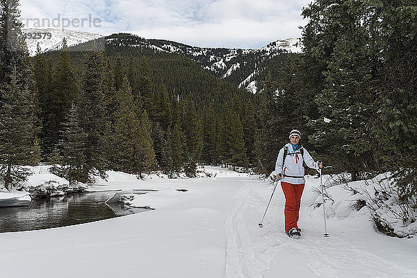 Frau auf Schneeschuhen durch verschneiten Wald  Berge