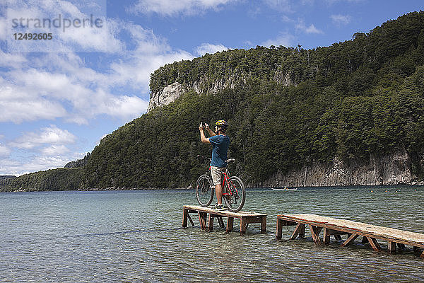 Fahrradfahrer macht Foto auf kleinem Steg am Bergsee
