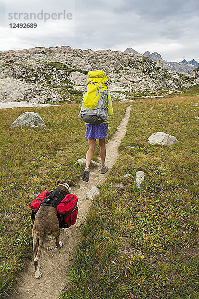 Eine Frau und ihr Hund wandern auf dem Weg ins Titcomb Basin in der Wind River Range  Bridger Teton National Forest  Pinedale  Wyoming.