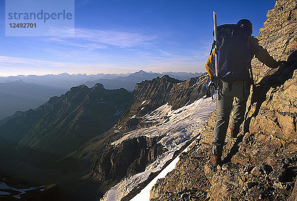 Bergsteiger auf einem schmalen Felsvorsprung über Tal und Berge