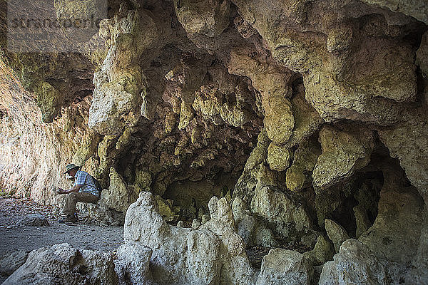 Wanderer sitzt an Grotte in Mckittrick Canyon