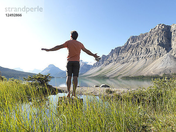 Mann balanciert auf einem Felsen über einem Alpensee
